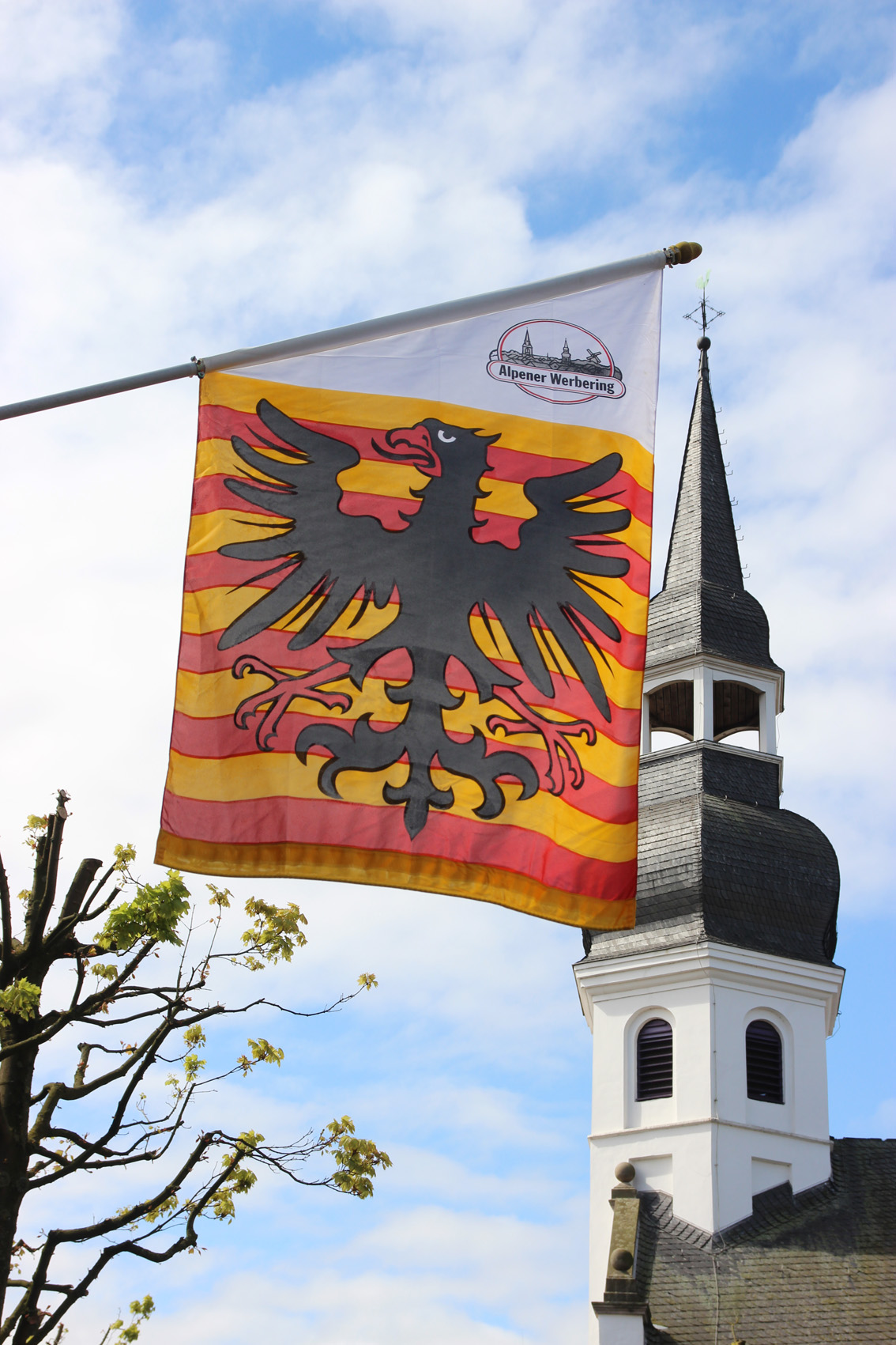 Fahne Gemeinde Alpen vor dem evangelischen Kirchturm als jpg-Datei